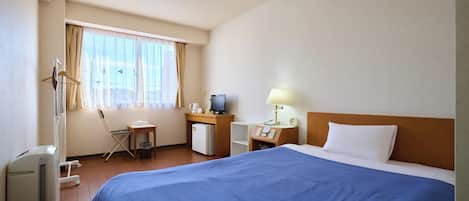 Habitación de hotel con una cama grande, un escritorio con computadora, una silla y una ventana con cortinas.