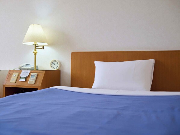 A hotel room with a wooden headboard, a bedside table with a lamp, a clock, and a phone. - Hotel Sincerity kani (Kani)