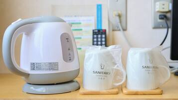 A kettle, two sanitary bags, and a power outlet on a wooden surface.