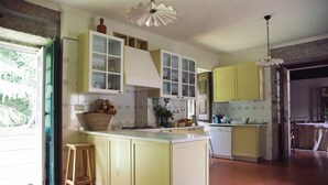 A kitchen with a central island, yellow cabinets, and a hanging light fixture. - Casa da Arosa Rural Tourism (Gandarela)