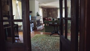 A traditional living room with a fireplace, green sofa, and a patterned rug. - Casa da Arosa Rural Tourism (Gandarela)