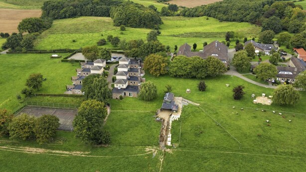 An aerial view of a rural area with a cluster of houses surrounded by fields and trees.