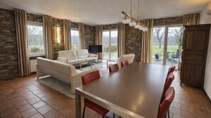 A spacious living room with a large dining table, a sofa, and a TV.