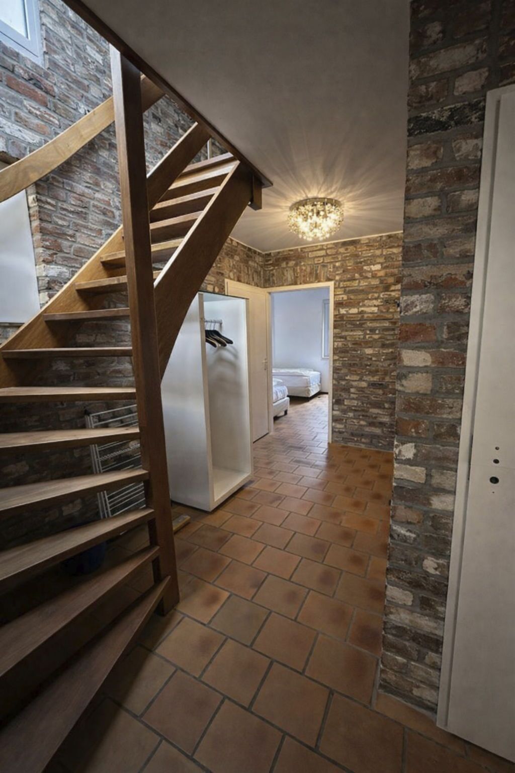 Eine Treppe führt zu einem Schlafzimmer mit einer Steinsandsteinwand und einer Kronleuchter.