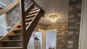 A staircase leading to a bedroom with a stone wall and a chandelier.