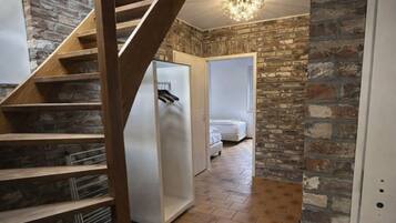 Eine Treppe führt zu einem Schlafzimmer mit einer Steinsandsteinwand und einer Kronleuchter.