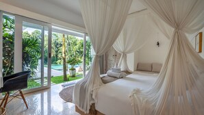Quarto com cama grande, cortinas leves, vista para o verde e design moderno.