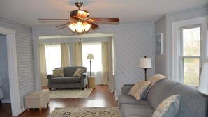 A living room with a grey sofa, a ceiling fan, and a window with curtains. - 4 Bedroom Home Near Warren Dunes State Park (Sawyer)