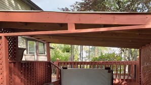 A wooden deck with a hot tub, a covered seating area, and a view of the surrounding trees. - 4 Bedroom Home Near Warren Dunes State Park (Sawyer)