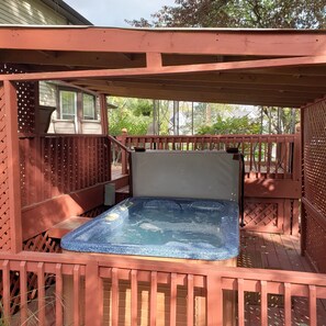 A wooden deck with a hot tub, a covered seating area, and a view of the surrounding trees. - 4 Bedroom Home Near Warren Dunes State Park (Sawyer)