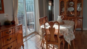 A dining area with a table set for four, wooden chairs, a chandelier, and a cabinet with dishes. - 4 Bedroom Home Near Warren Dunes State Park (Sawyer)