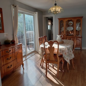 A dining area with a table set for four, wooden chairs, a chandelier, and a cabinet with dishes. - 4 Bedroom Home Near Warren Dunes State Park (Sawyer)