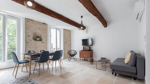 Zona d'estar àmplia amb taula de dinar, cadires, sofà i televisió.