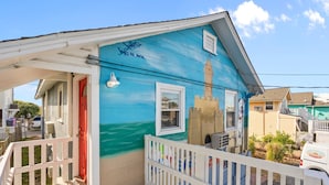A small, colorful house with a red door, a white porch, and a small balcony. - Vitamin Sea Suites 4: Downtown and a short walk to the SEA! (Carolina Beach)
