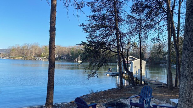 Una cabaña junto al lago con asientos exteriores y un muelle.