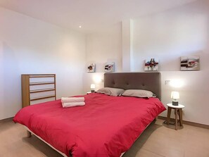 Quarto bem arrumado com uma cama grande, mesas de cabeceira e obras de arte penduradas na parede.