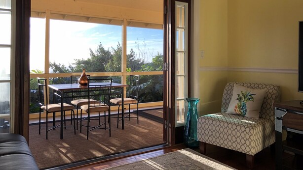 A room with a sliding glass door leading to an outdoor patio area with a table and chairs. - New Listing: Spacious Suite for 4x with panoramic ocean view (Kailua)
