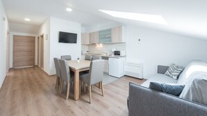 Ein moderner, kompakter Wohnbereich mit Essplatz, Küchenzeile und Sofa.
