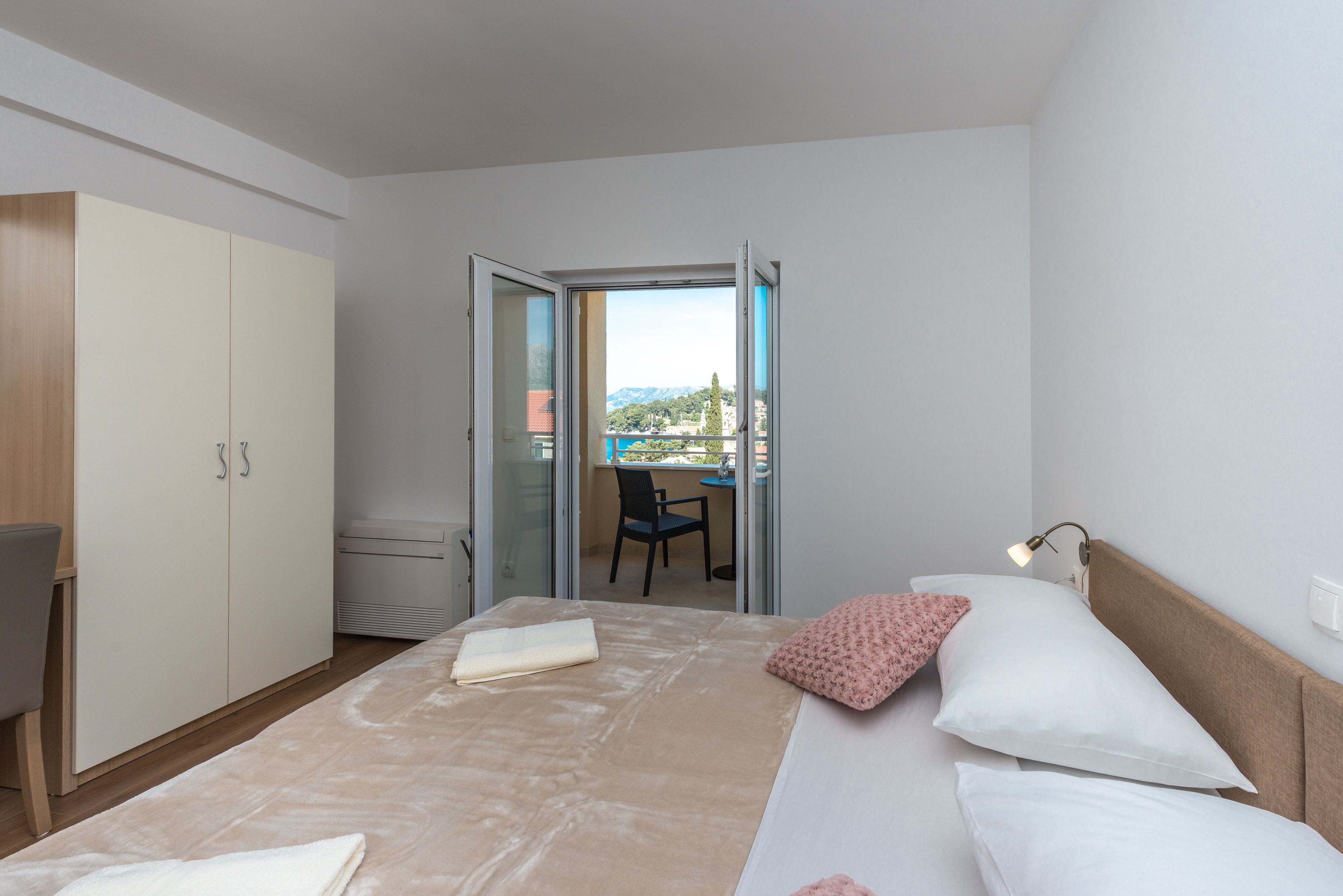 Una habitación de hotel con cama, escritorio y balcón con vistas.