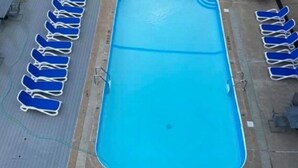 Piscina rectangular amb aigua blava, envoltada per files de gandules blaves.
