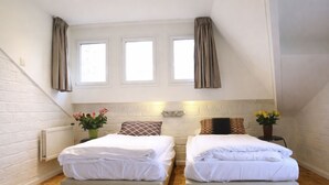 Une chambre avec deux lits, un radiateur et une fenêtre avec des rideaux.