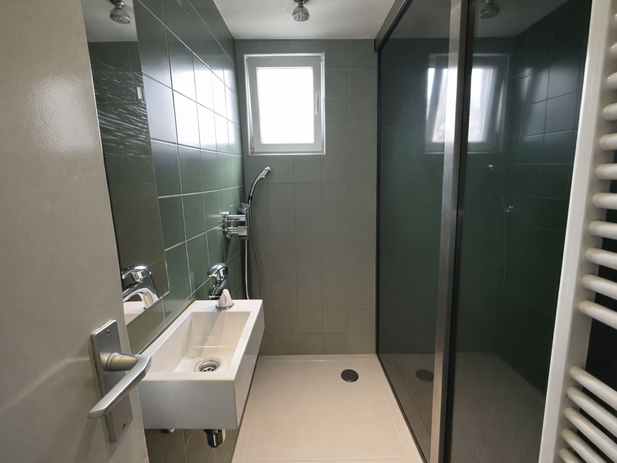 Une salle de bain moderne avec une douche, un lavabo et une fenêtre.