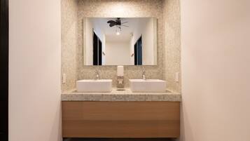 A modern bathroom with two sinks, a large mirror, and a ceiling fan.