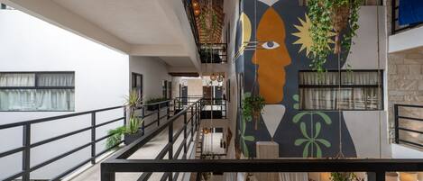 A multi-level interior with a modern design, featuring a staircase, balconies, and a mural on the wall.