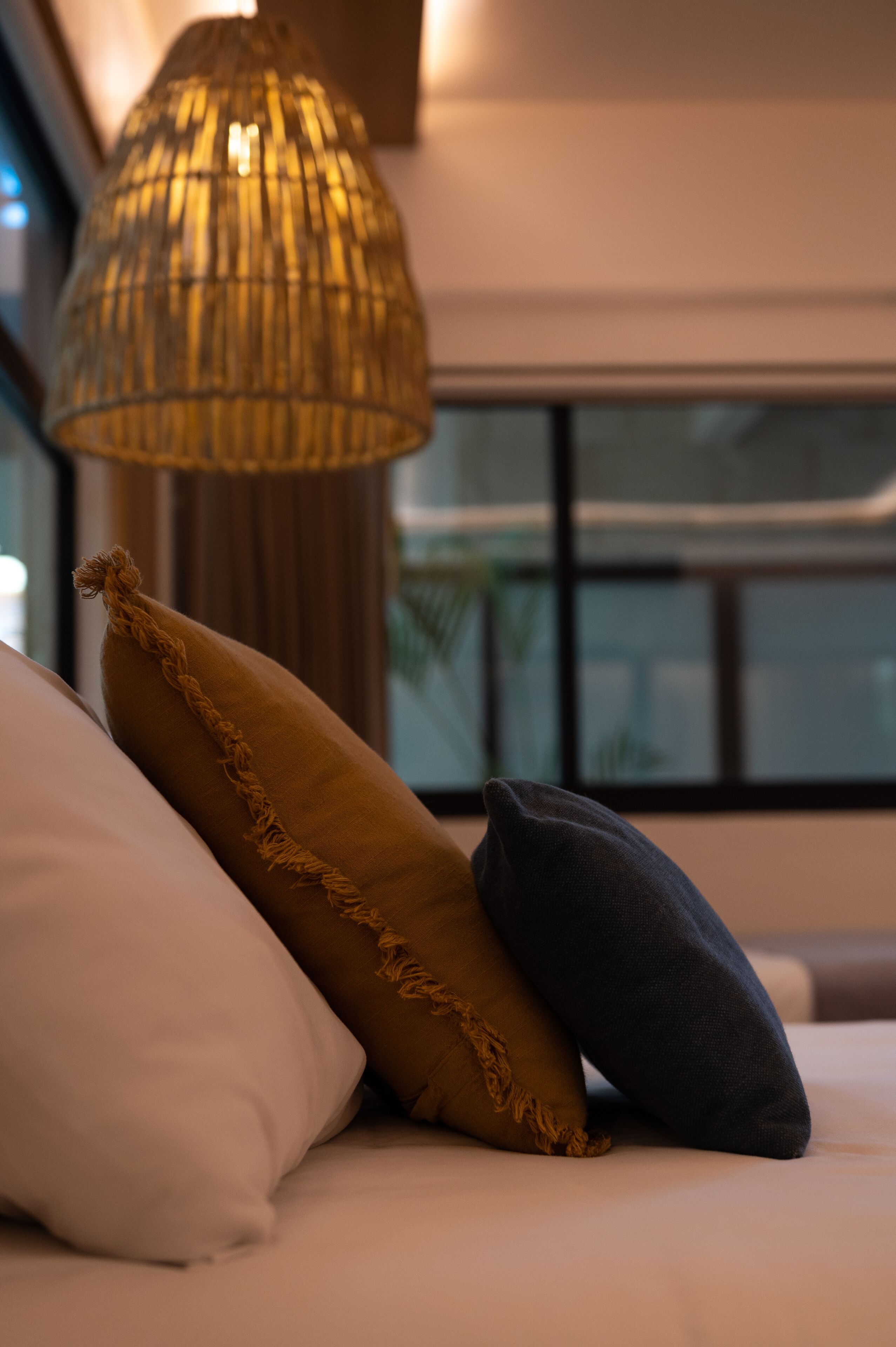 Una cama con tres almohadas y una lámpara colgante.