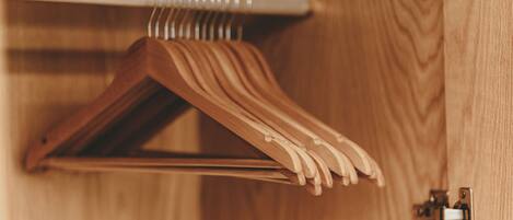 A wooden hanger rack with multiple hangers, a metal rod, and a door latch.