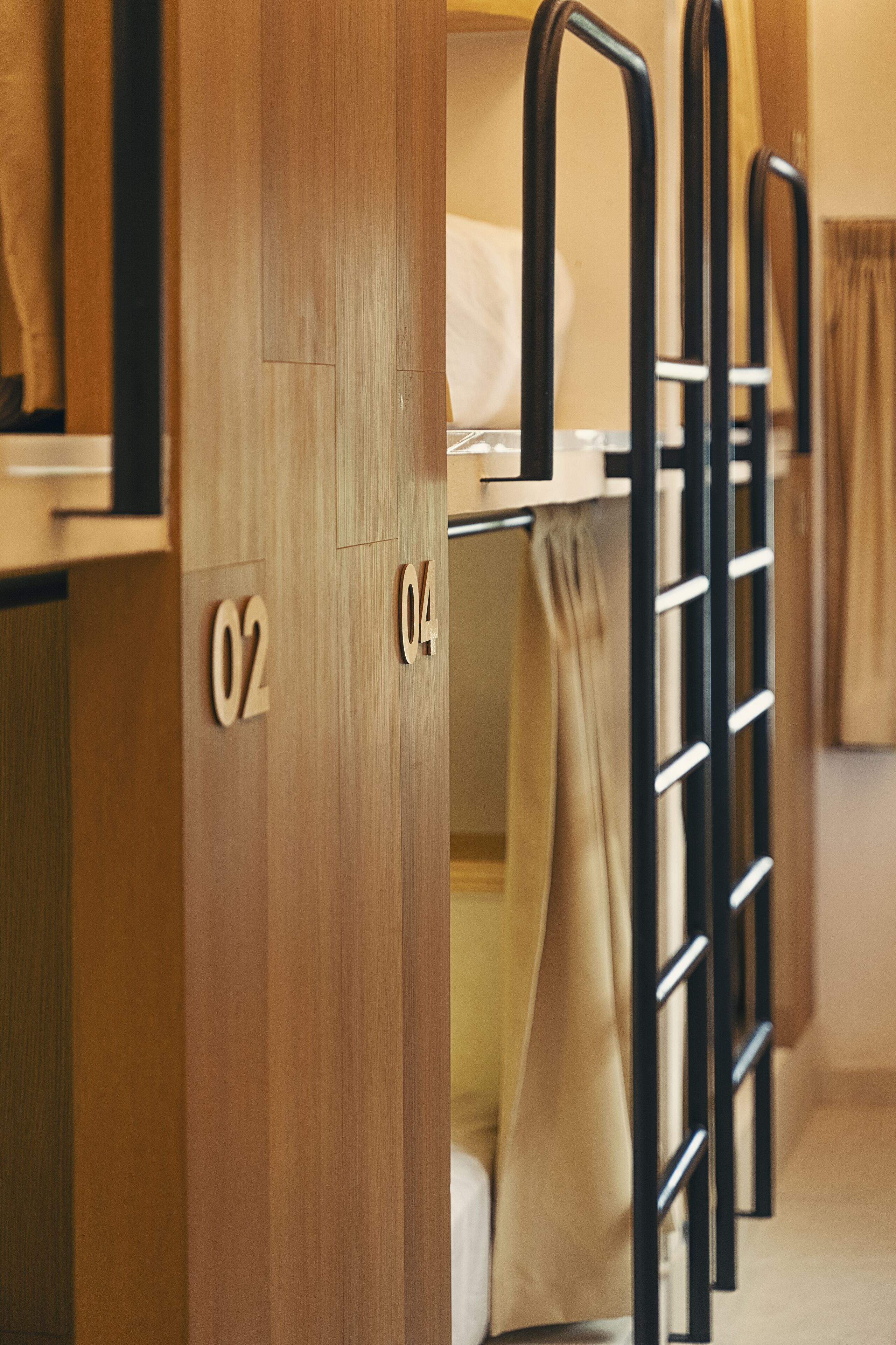 Una habitación de hotel con literas, puertas numeradas y una cortina.