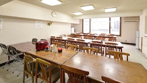 A conference room with multiple tables and chairs, equipped with ceiling lights, a clock, and a calendar on the wall. - Hotel Million (Muroran)