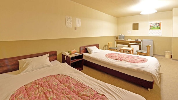 A hotel room with two beds, a desk, a chair, a television, and a small kitchenette. - Hotel Million (Muroran)