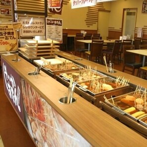 A buffet counter with multiple food stations, a wooden counter, and signs in a foreign language. - Rest Inn Tokinosumika (Gotemba)