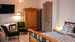 A bedroom with a wooden bed, a green chair, a wooden wardrobe, and a television on the wall. - Dom na Skraju by Interhome (Lubomierz/Gryfow Slaski)