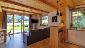 A modern kitchen with wooden cabinets, a built-in island, and a large window offering a view of the outdoors. - Chaty Pod Beskidkiem by Interhome (Szczyrk)