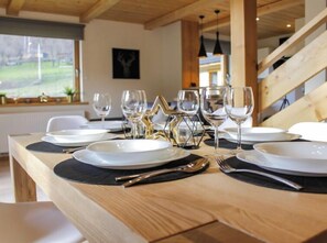 Enjoy a meal in this elegant dining area with a wooden table, white plates, and fine cutlery.