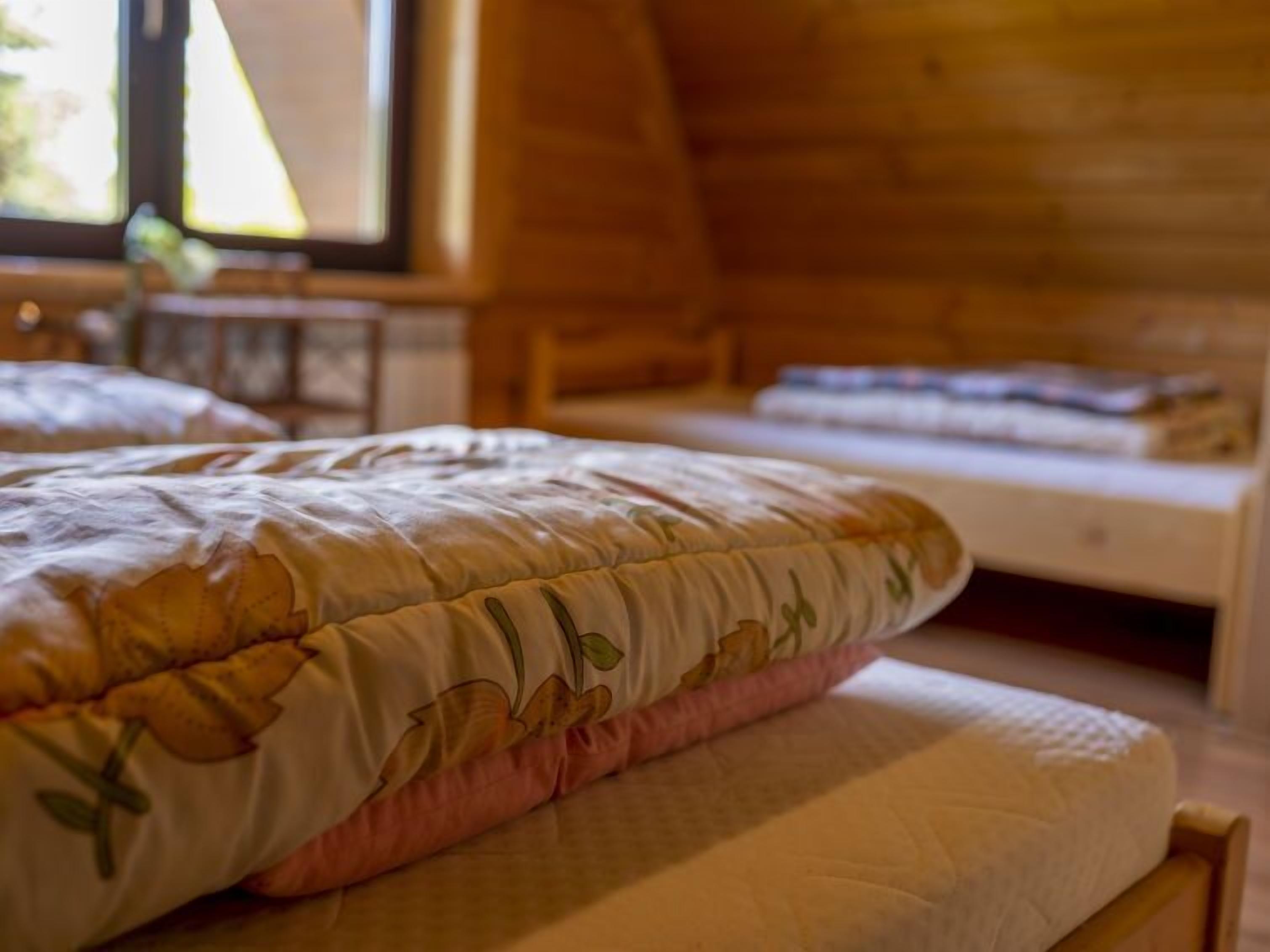 Un dormitorio acogedor con techo de madera, una cama con colcha floral y una mesita de noche con lámpara.