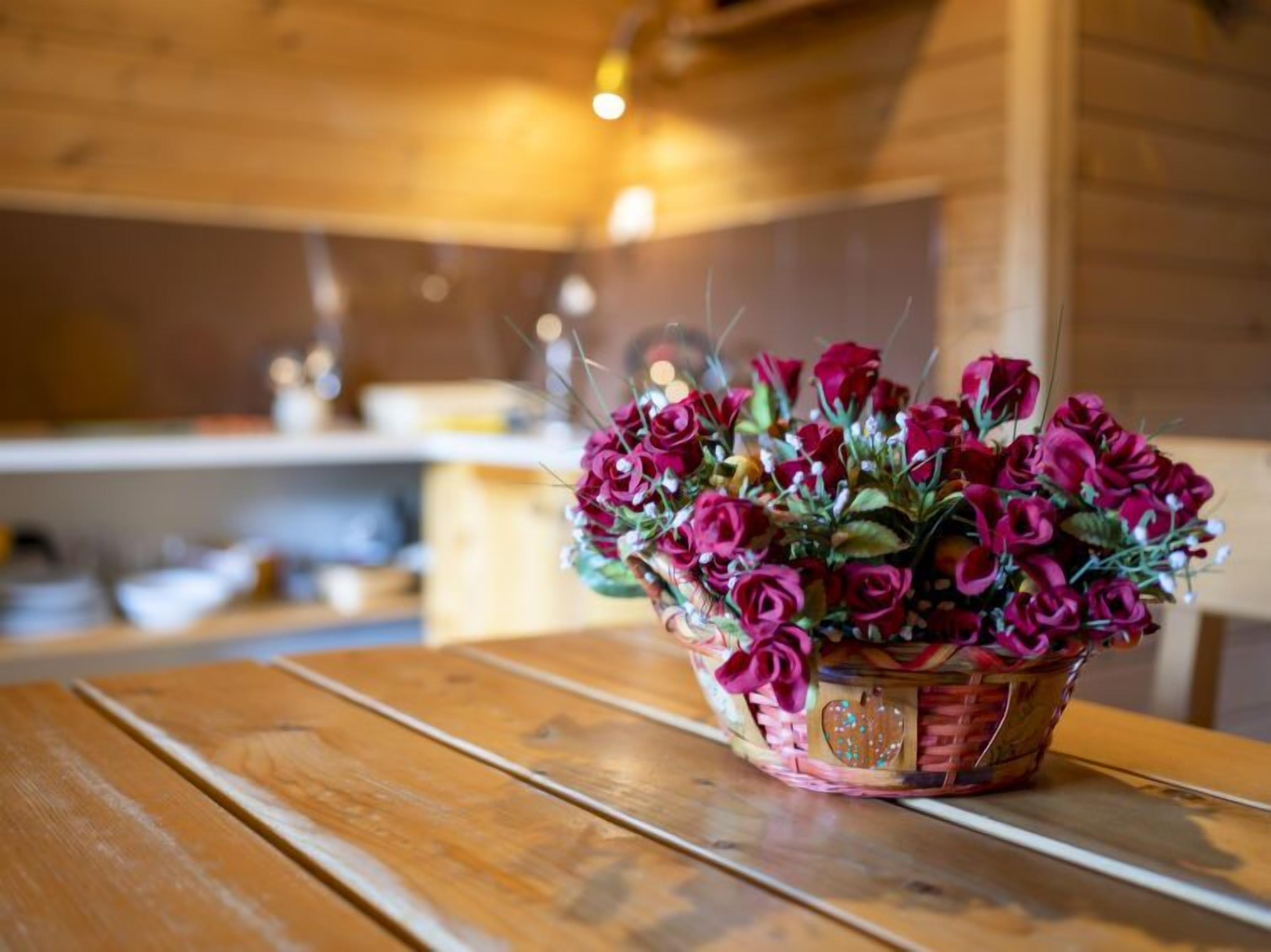 Une table en bois avec un panier de roses rouges.
