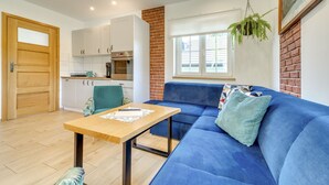 A modern living room with a blue sofa, a wooden coffee table, and a kitchen in the background. - Siglanów by Interhome (Wisla)