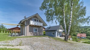 A house with a stone driveway, a balcony, and a view of the surrounding landscape. - Siglanów by Interhome (Wisla)