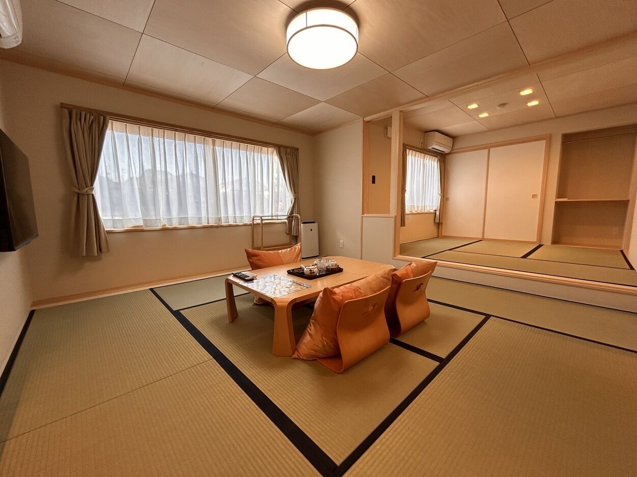 Um quarto japonês tradicional com tatames, uma mesa baixa com almofadas e portas deslizantes.