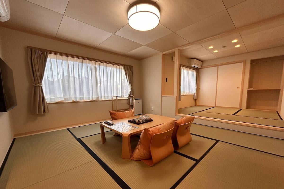 Um quarto japonês tradicional com tatames, uma mesa baixa com almofadas e portas deslizantes.