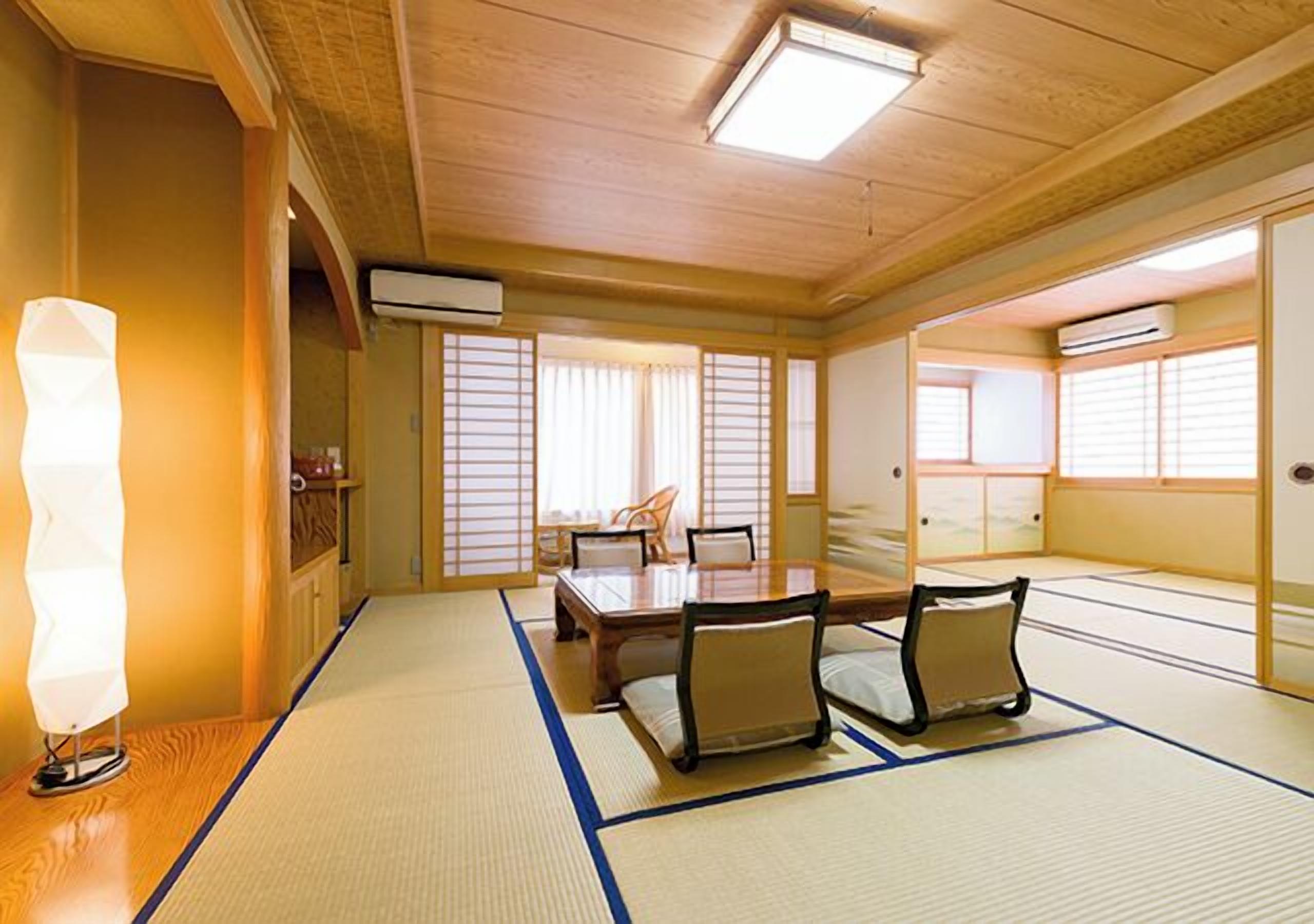 Um quarto japonês tradicional com tatames, uma mesa baixa com almofadas e portas deslizantes.