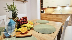 Une cuisine moderne avec des meubles en bois, un plan de travail et un coin repas agrémenté d’un panier de fruits et de verres.