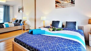 Une chambre d’hôtel avec un grand lit, une table de chevet, une commode, un miroir et un tableau accroché au mur.