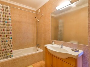 Un baño con bañera, lavamanos y espejo.
