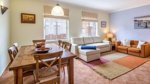 A living room with a dining area, a sofa, a coffee table, and a lamp. - Grand Beach Hit by Interhome (Pêra)
