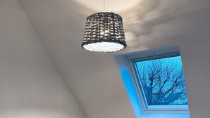 Een kleine, moderne slaapkamer met twee bedden, een dakraam en een hanglamp.