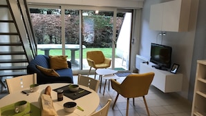 Een moderne woonkamer met een bank, stoelen, een eettafel en een televisie.
